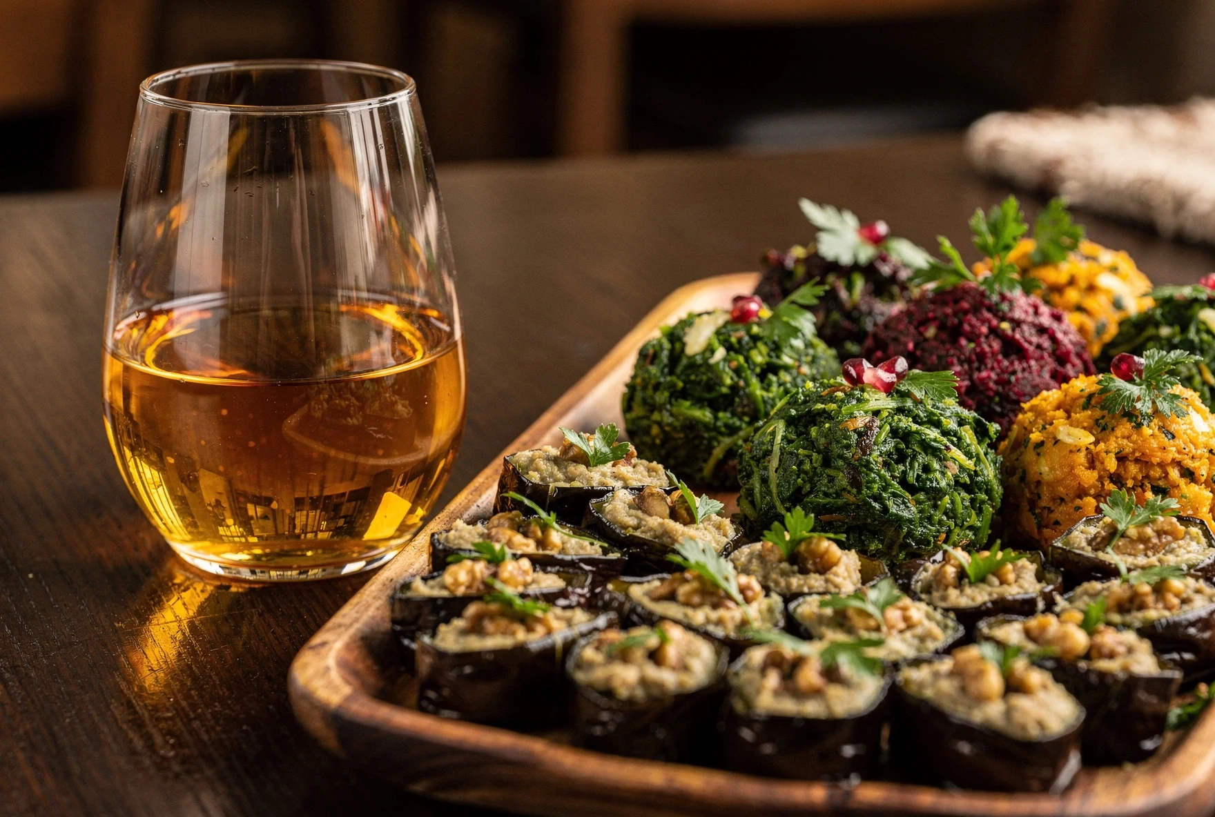 Glass of amber wine alongside Georgian appetizers including badrijani eggplant rolls and pkhali