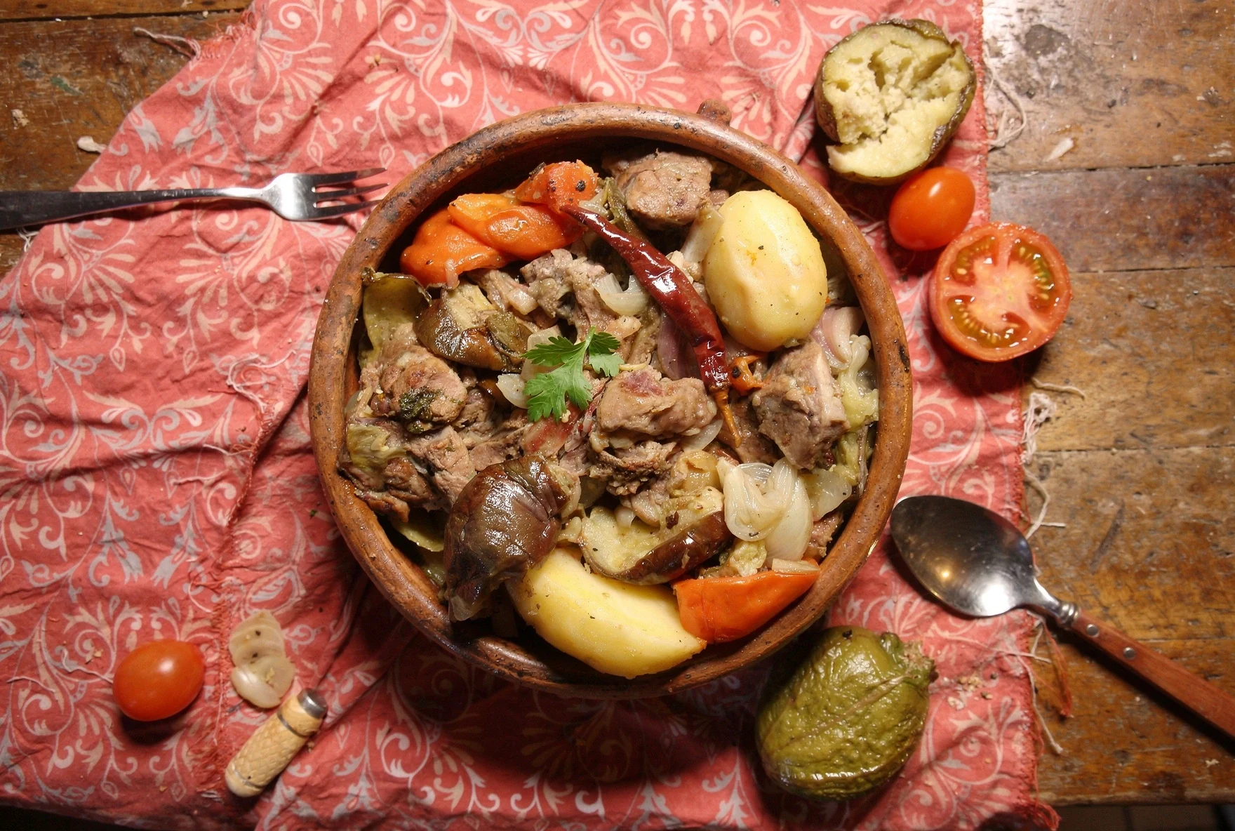 Layering vegetables and herbs into a clay pot for Georgian chanakhi