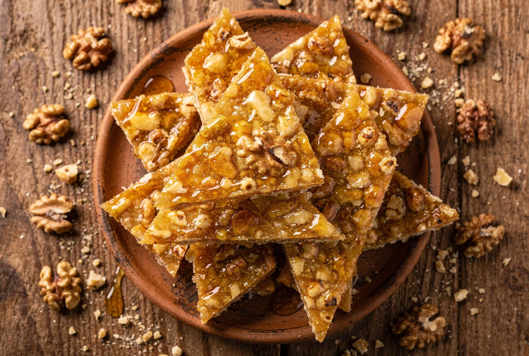 Golden gozinaki honey walnut brittle cut into diamond shapes on a clay plate