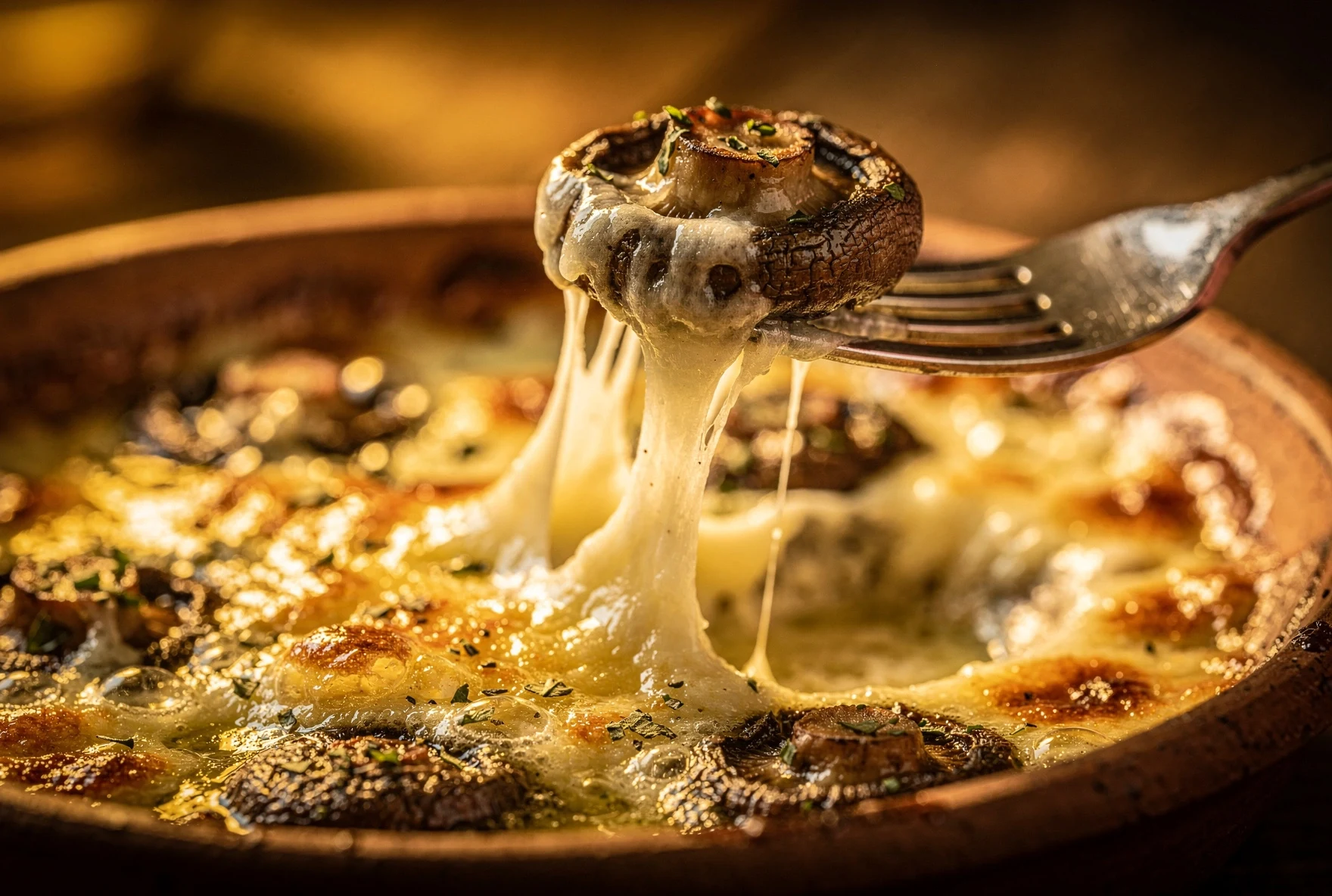 Baked mushroom with melted sulguni cheese being lifted from a Georgian clay ketsi dish