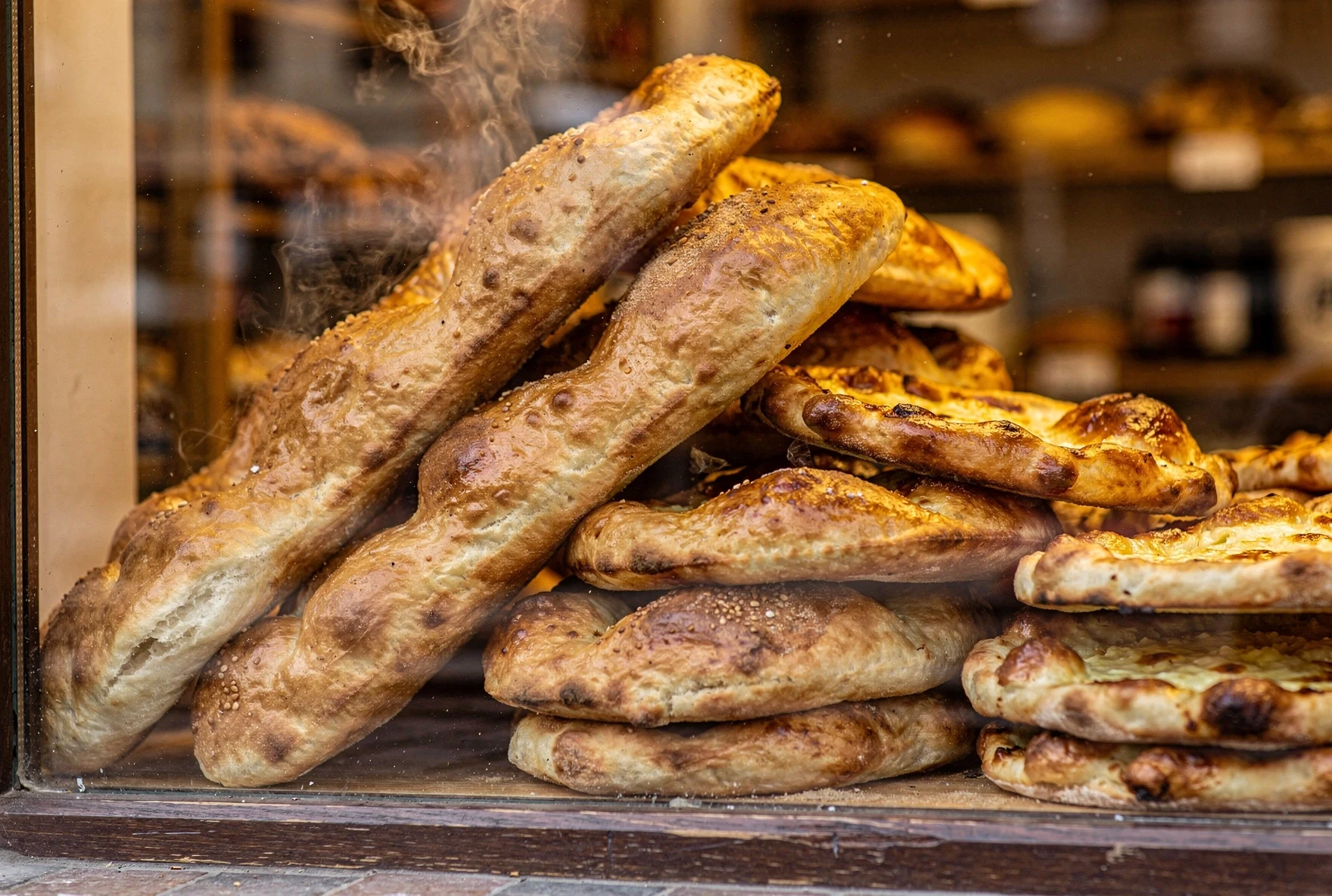 Georgian bakery window displaying freshly baked shotis puri bread with steam rising